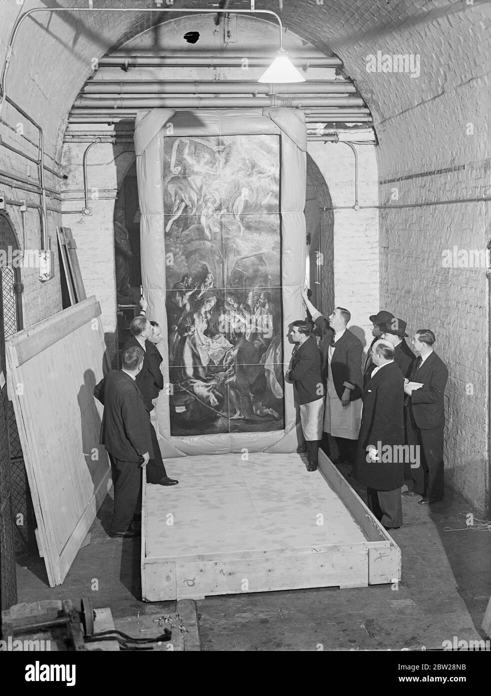 The famous painting 'Adoration of the Shepherds' by El Greco as arrived at the Royal Academy in London after being transported under armed guards from Romania. The picture has been lent by King Carol of Romania for the Exhibition of European Art of the 17th century opening at Burlington House early in June. Photo shows, the picture 'Adoration of the Shepherds' being unpacked and past by a customs official at Burlington House. Right (nearest camera) is Mr Blackley, who had charge of it journeys journey. 22 December 1937 Stock Photo