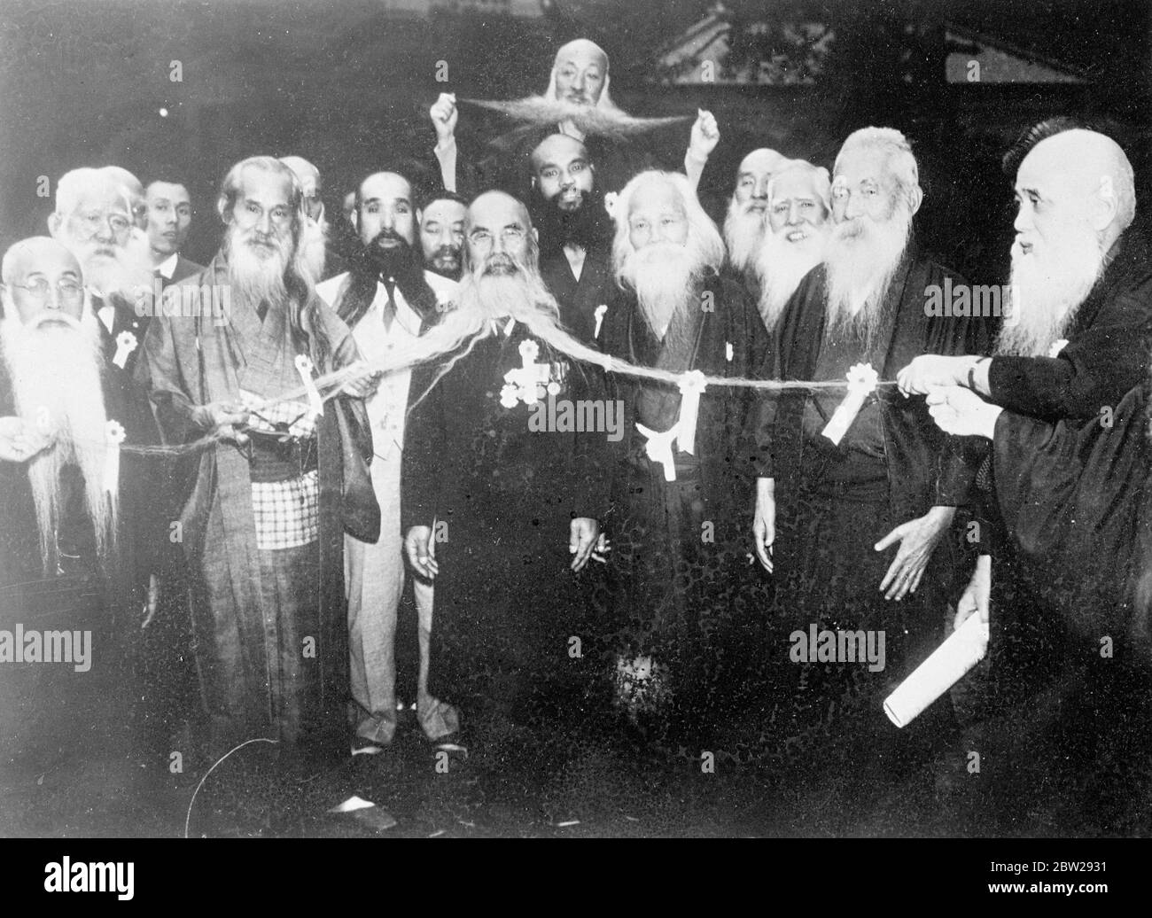 The man with the six-foot whiskers!. The be whisked, delighted friends of Naojiro Kato proudly extend to full view his magnificent whiskers at a 1936 championship beard contest, which measure 79 inches from tip to tip. The whiskers of the gentleman behind appear quite insignificant in comparison. Stock Photo