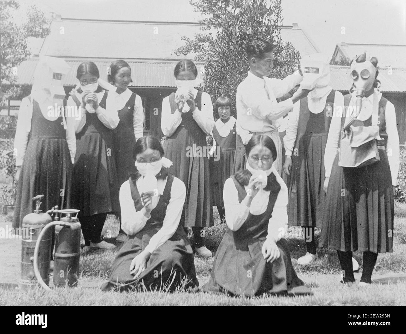 Tokyo school gives children gas mask lessons. Training in how to wear gas masks, is now included in the curriculum of girls schools in Japan as part of the war. Training of the civil population. Photo shows, girls of a Tokyo high school, wearing modern 'gym frocks', practising with different types of gas masks. 22 November 1937 Stock Photo