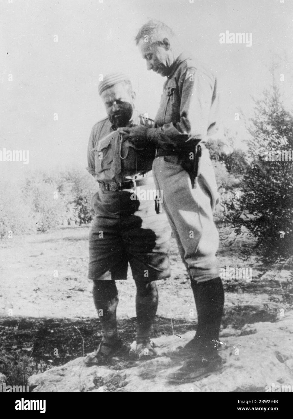 First pictures of the new Palestine troubles. Rebel leader at his secret headquarters. This picture, just received from Palestine, shows Farozi Kawkji (left), notorious Arab agitator, and his side de camp, at the secret headquarters from which he is conducting the series of Arab raids and other outrages which have led to drastic reprisals by the British authorities. Although a fanatical patriot, it will be noted that Kawkji is discarded the traditional dress of his people and has adopted khaki shirt and shorts. 20 October 1937 Stock Photo
