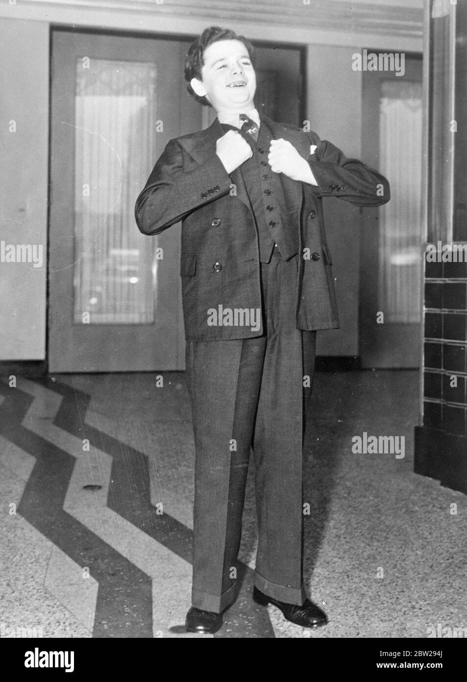 Freddie Bartholomew showrooms long trousers and manly pride. Freddie Bartholomew, the young film actor, who had been the subject of long drawnout litigation in the American courts, thrust out his chest and laughs in manly fashion after donning his first pair of long trousers. To celebrate the occasion, Freddie attended the premiere of Greta Garbo's new film 'Conquest 'in Los Angeles. 1 November 1937 Stock Photo