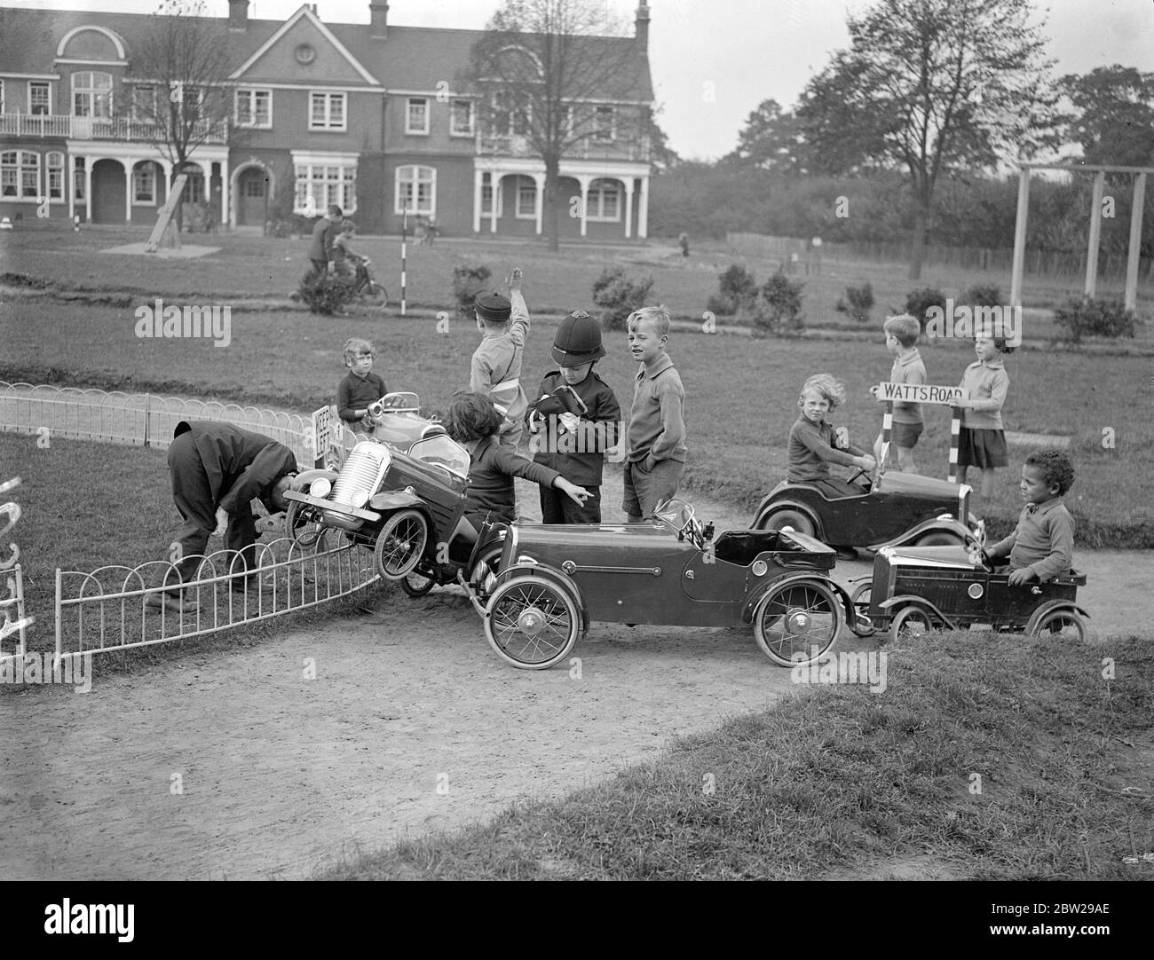 Children taught road sense on their own highway at Essex school. To teach road sent to the 500 pupils at the Hutton (ICC) residential school near Brentwood, Essex, a miniature complete road system with all approved highway signs has been laid out by the pupils in part of the grounds. Children actors 'policeman'while others drive toy motors to and fro. One section of road is permanently 'up'. The scheme is the idea of the headmaster, Mr RC Higdon and he has also instituted and offenders court. Photo shows, a crash between two toy cars at a roundabout on the miniature highway went to drivers dis Stock Photo