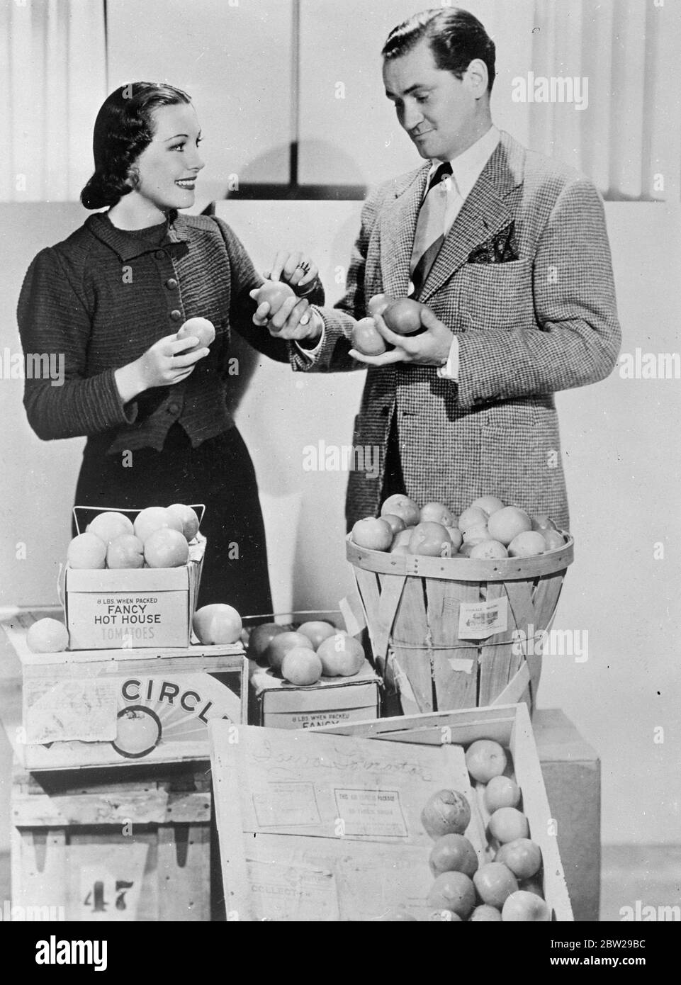 She wanted one with most 'squelch'. Gladys Swarthout, famous singer of opera and films, had one of the strangest requests when she sought the tomato with the softest flesh and most 'squelch'. The tomato was needed for her new film in which a hostile member of the audience throws it in her face. Hundreds of tomatoes, was sent by air from all parts of the country to Hollywood, to the indignation of the Los Angeles and Hollywood Chambers of Commerce. Photo shows, Gladys Swarthout with her husband and manager, Frank Chapman, selecting the appropriate tomato from a consignment sent by air from Miam Stock Photo