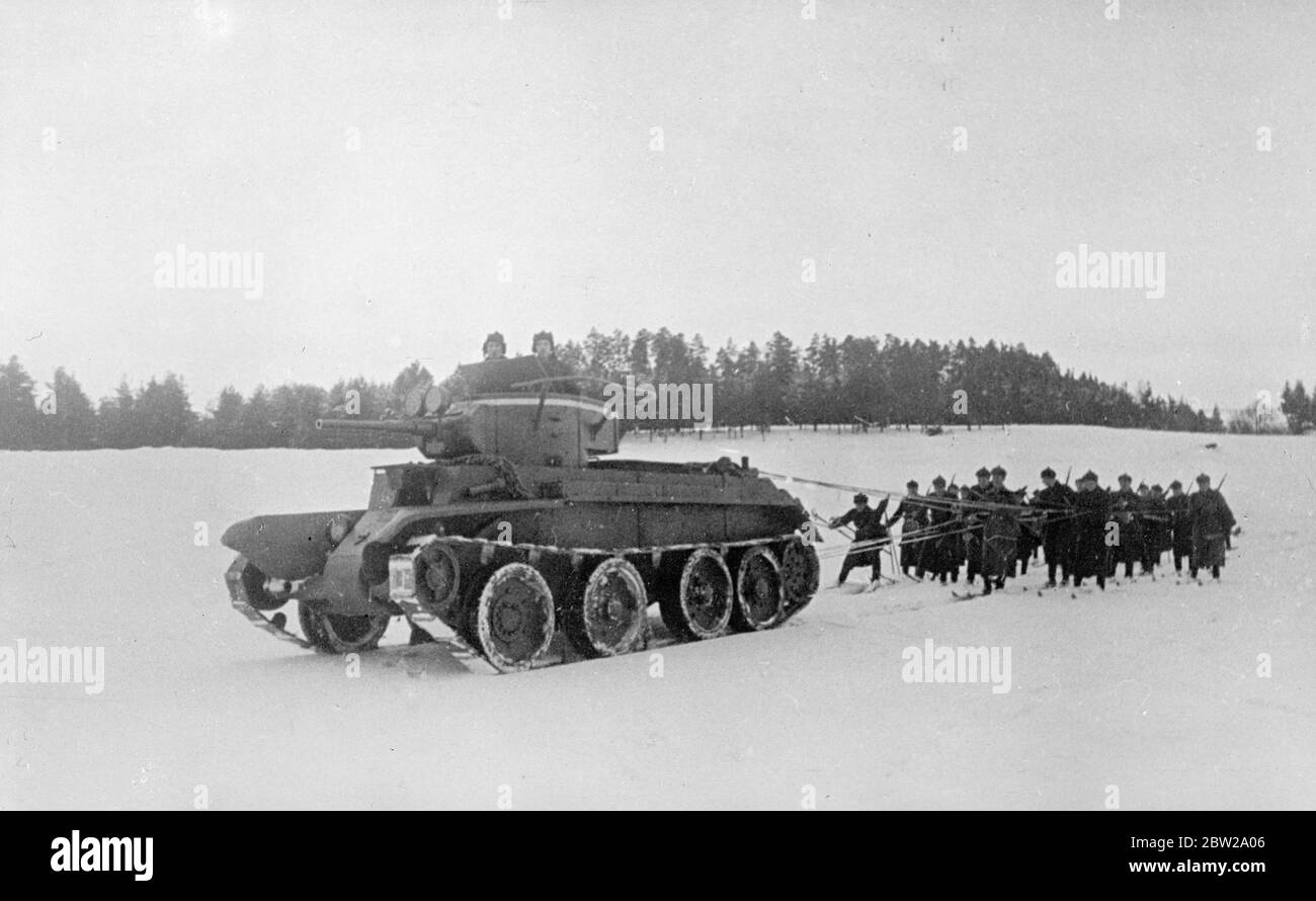 Taken in tow by a tank. Soviet infantryman on skis. Big tanks provided motive power for platoons of infantryman on skis when winter tactical exercises, was staged by the red Army near Moscow. Photo shows, a rifle platoon on skis holding to tie roads as a tank pulled them over the snow. 13 November 1937 Stock Photo