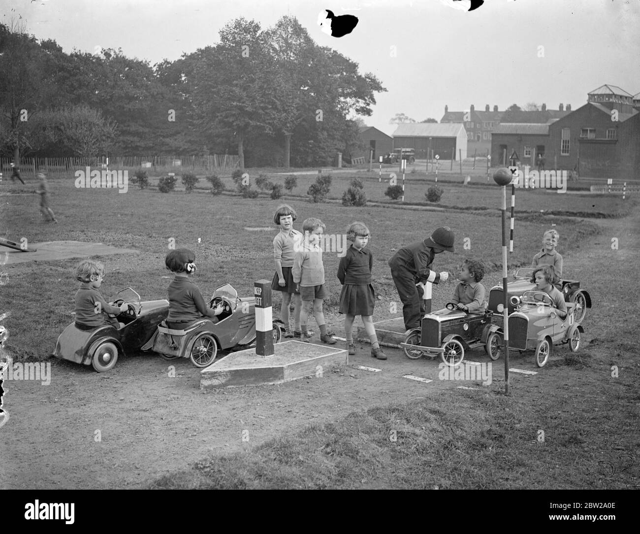 Children taught road sense on their own highway at Essex school. To teach road sent to the 500 pupils at the Hutton (ICC) residential school near Brentwood, Essex, a miniature complete road system with all approved highway signs has been laid out by the pupils in part of the grounds. Children actors 'policeman'while others drive toy motors to and fro. One section of road is permanently 'up'. The scheme is the idea of the headmaster, Mr RC Higdon and he has also instituted and offenders court. Photo shows, a child motorist being cautioned by juvenile policeman for passing the pedestrian crossin Stock Photo