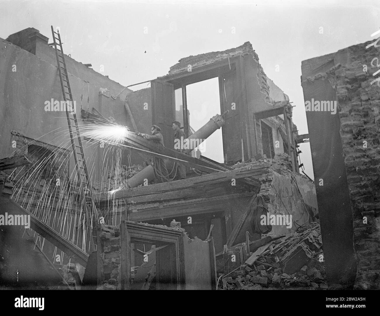 Where 'stars' of the national theatre will 'Scintiliate'. Workmen with an Oxy acetylene torch sends up a row of molten metal as he cuts away girders during the demolition of buildings to make way for the new National Theatre on a site situated near the Victoria and Albert Museum, Kensington, London. 2 December 1937 Stock Photo