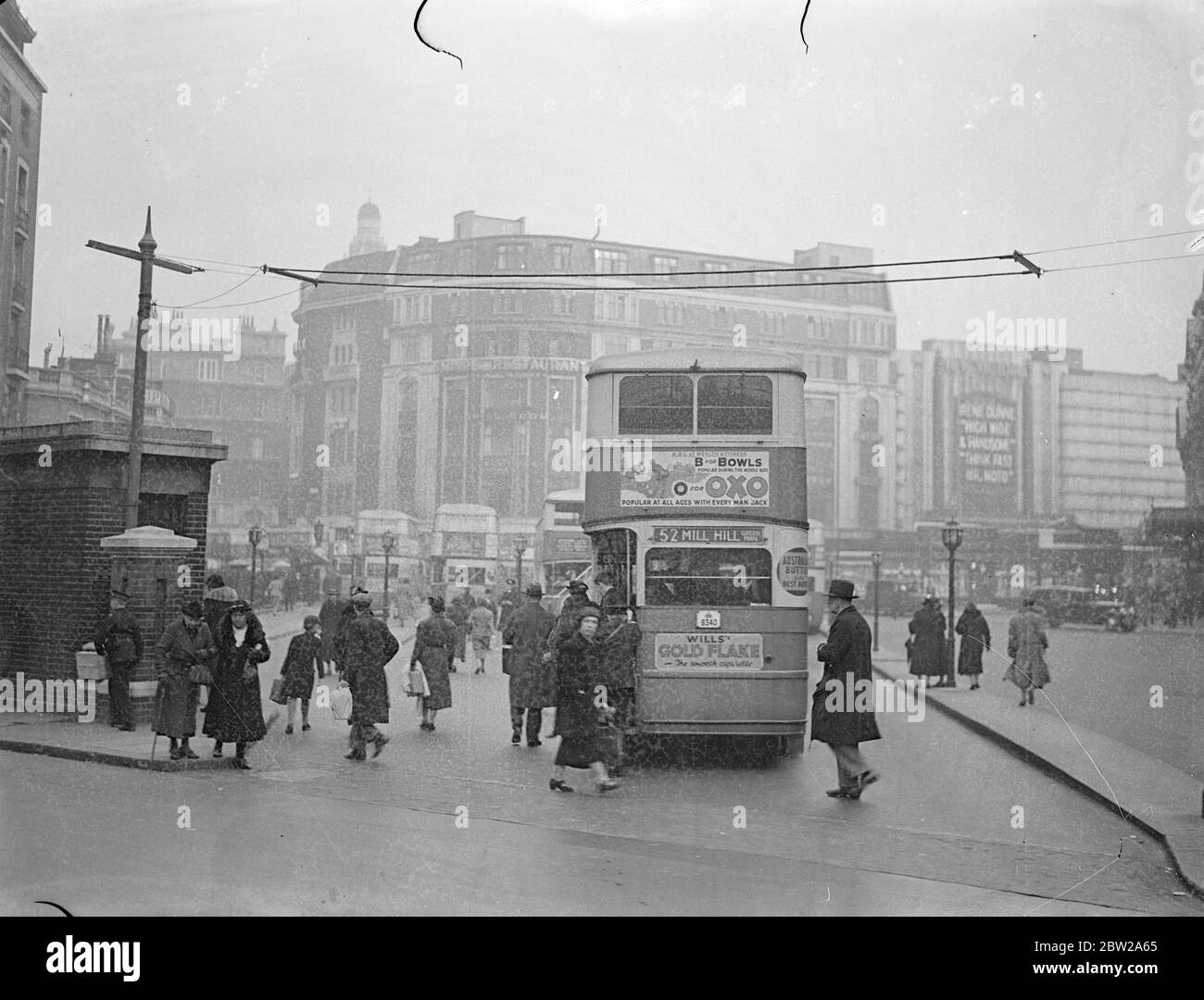 London buses to record their own movements by electricity. The first overhead wire, looking something like a wireless aerial has been erected near the forecourt of Victoria station in preparation for an experiment by London transport, which, it is hoped, will enable the movements of all buses to be automatically recorded on dials at the board's headquarters and congestion relieved. The buses will carry on the roof coil of wire through which will pass an alternating current. The instant of bus passes underneath the wire, the current in the coil on the roof will induce a current in the fixed wir Stock Photo