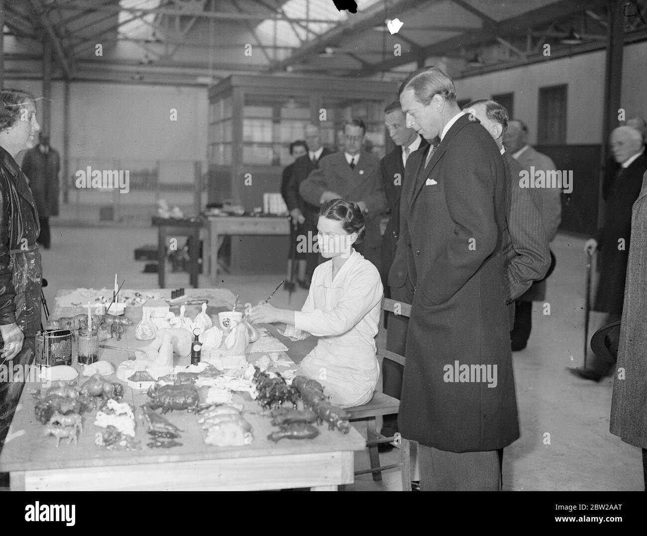 Duke of Kent, tours Treforest Trading Estate during South Wales visit. Motoring from St Fagan's Castle, where he stayed with Lord Plymouth, the Duke of Kent, told the Treforest Trading Estate on the second day of his two-day visit to South Wales. The estate, which is 3 miles from Pontypridd, was established as a means of attracting new industries to South Wales. The company is financed by the Government. Photo shows, the Duke of Kent, watching a girl worker making toys and one of the factories on the Treforest Trading Estate. 20 October 1937 Stock Photo