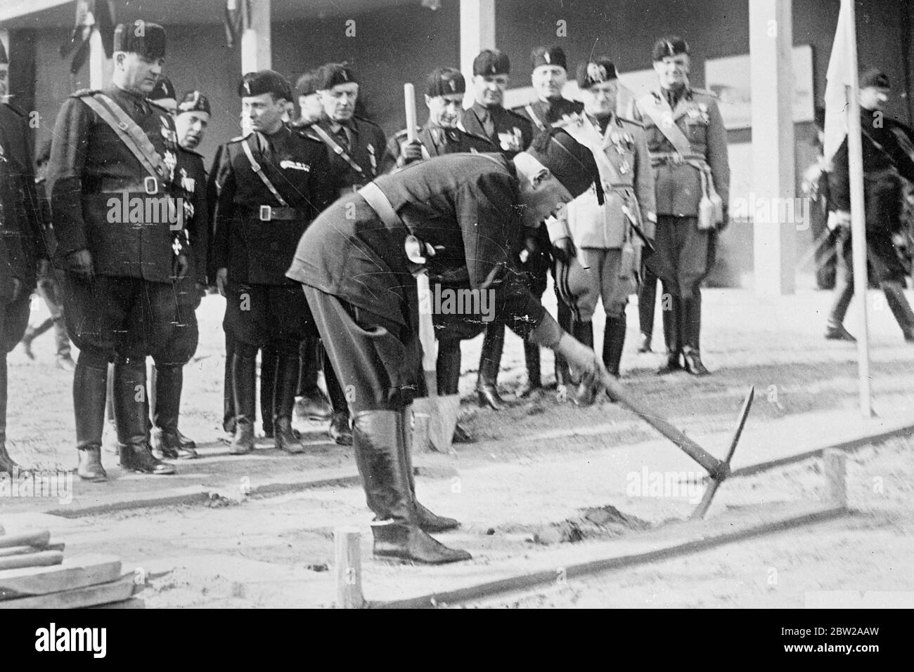Mussolini gets in his point-with a pick-axe. Signor Mussolini wielding a pick-axe as he officially inaugurated the excavation work for the new 'Littoria House' building in Rome. The building is part of the scheme of improvements for the 16th year of the Fascist era the opening of which has just had celebrated. 1 November 1937 Stock Photo