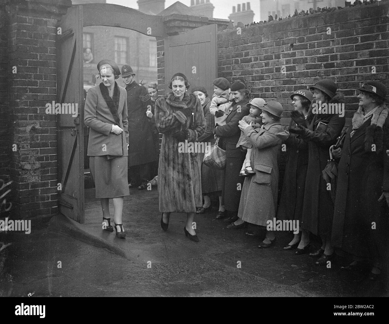 Duchess of Kent, celebrating birthday, visit Occupational Training Centre for Physically Handicapped. The Duchess of Kent, celebrated her birthday by visiting the headquarters and training centres of the Council for the promotion of Occupational Industries among the Physically Handicapped. When she called at the St Leonard's Hall training centre in St Leonard Street, Bow, she received a birthday gift from Mr Richard Cronin. Photo shows, mothers and babies. Standing in the rain to greet the Duchess of Kent, when she arrived at St Leonard's Hall, St Leonard Street, Bow. 30 November 1937 Stock Photo