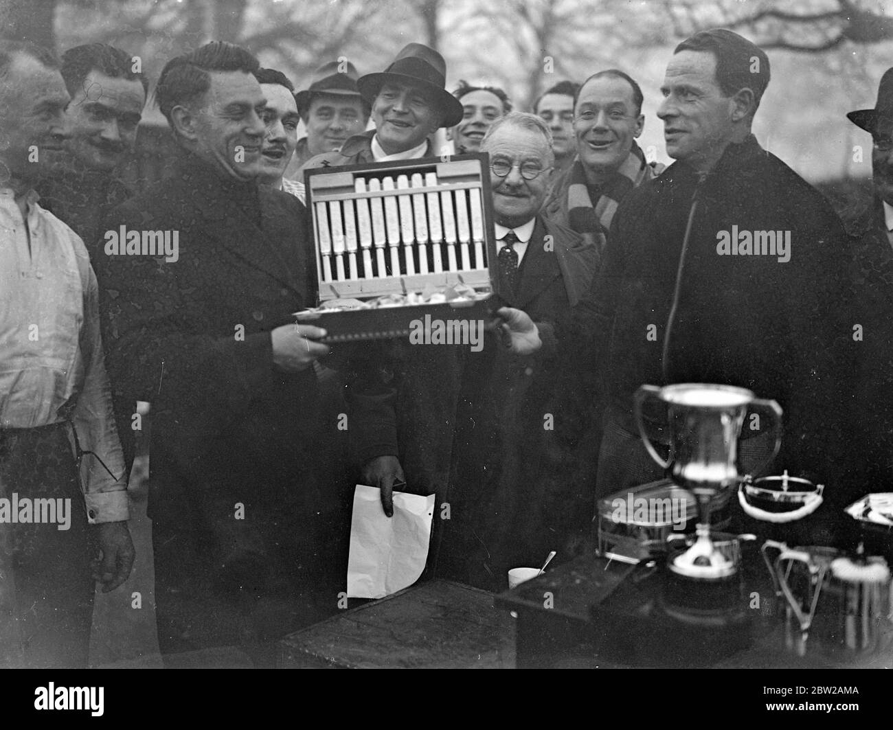 Serpentine swimmer receives canteen of cutlery for braving the 'cutting' cold. Despite the severe early morning cold, Hardy, members of the Serpentine Swimming Club took part in the final race of the winter competition in the Serpentine, Hyde Park. The winner was Reginald Pike, who received a canteen of cutlery. Photo shows, Mr A I Greenbury, President of the Serpentine Swimming Club (left) , presenting the canteen of cutlery to Reginald Pike, winner of the winter competition. 18 December 1937 Stock Photo