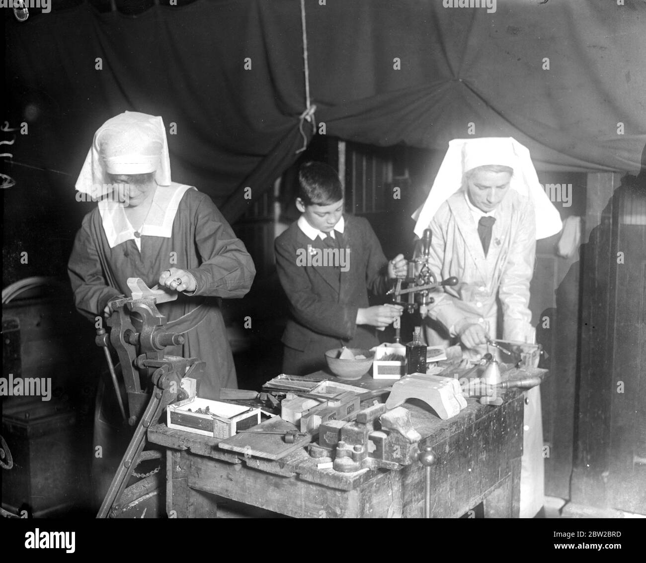 Exhibition of work done by the Wimbledon Women War Workers Depot. Mother and son on war wrok - A lady needleworker and a lady carpenter making parts of splints - The boy is the son of one of the ladies. 14 March 1917 Stock Photo