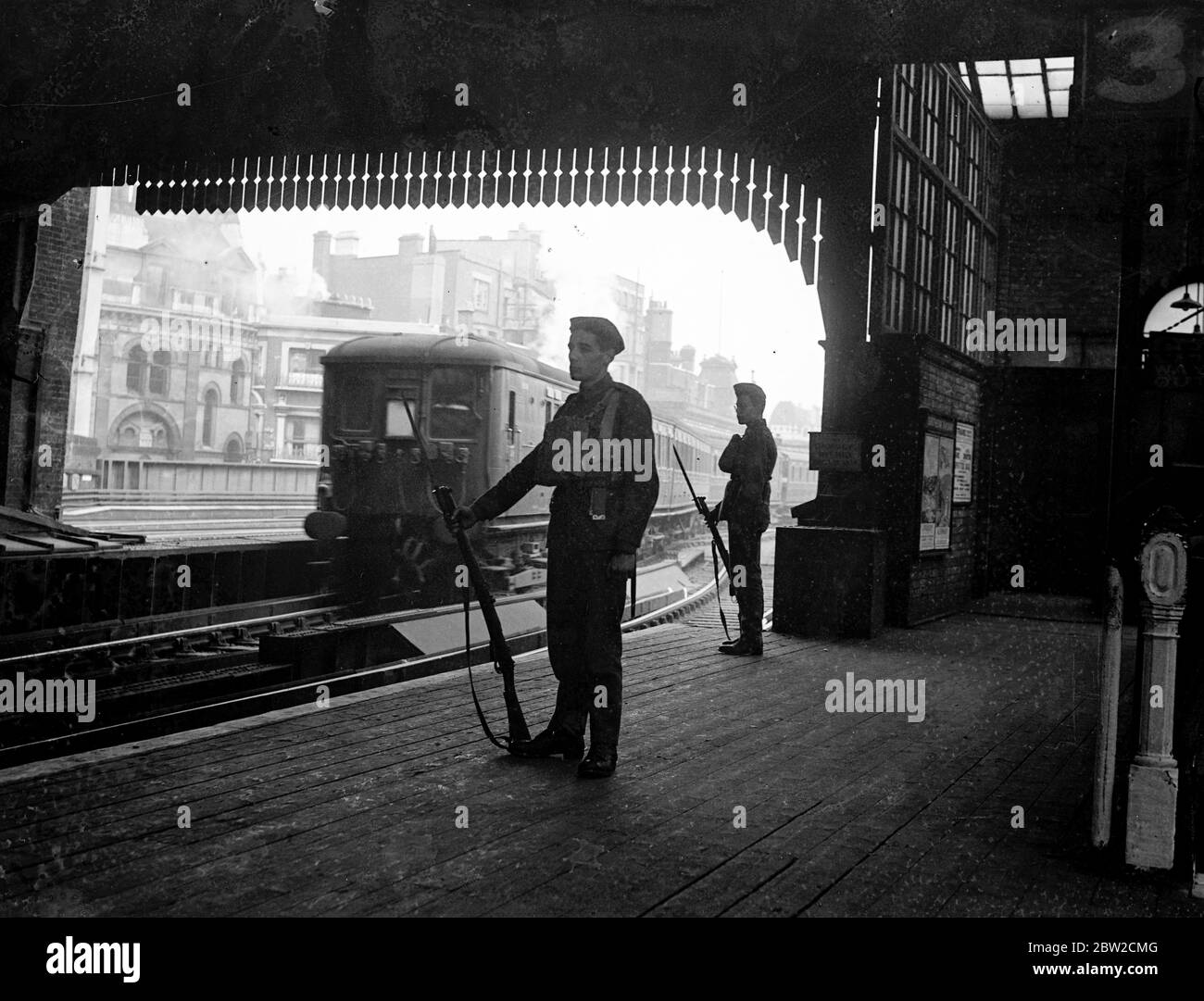 Military guards have been installed at vital points in London, including railway stations, goods yards and important municipal buildings. Military guards on a train platform at a London train station. 30 August 1939 Stock Photo