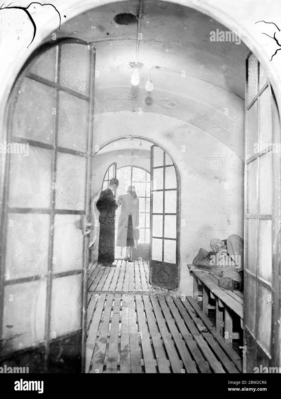 Britain's most luxurious air raid shelter has been built somewhere in Surrey. The shelter has three rooms, kitchenette, a shower and foot bath for decontamination purposes. The whole shelter, which methods 50' x 10' 6 x 8' 6 inches high, is encased in a shell of reinforced concrete, while the interior walls are faced with cement bricks. The reinforced concrete roof is no less then 2 1/2 feet thick. The shelter is equipped with electric light; if that should failed there is gas; if that fails there is a supply of oil lamps. There is bedroom accommodation in which 12 persons can be as comfortabl Stock Photo