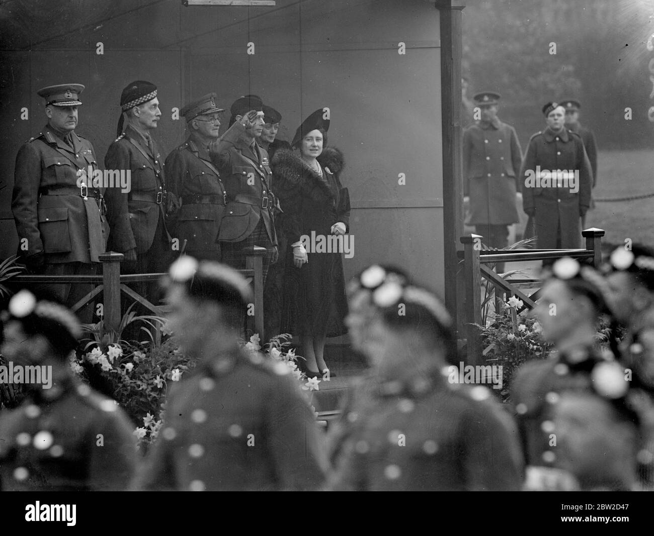 The King George VI and Queen Elizabeth, who have just returned from Sandringham, attended the dedication of the new West Wing of the St Andrews Garrison Church of Scotland at Aldershot Camp, Hampshire, and afterwards inspected the Scots regiments. Photo shows: The King and Queen at the saluting base. The King is in the uniform of one of the Scots regiment 5 February 1939 Stock Photo