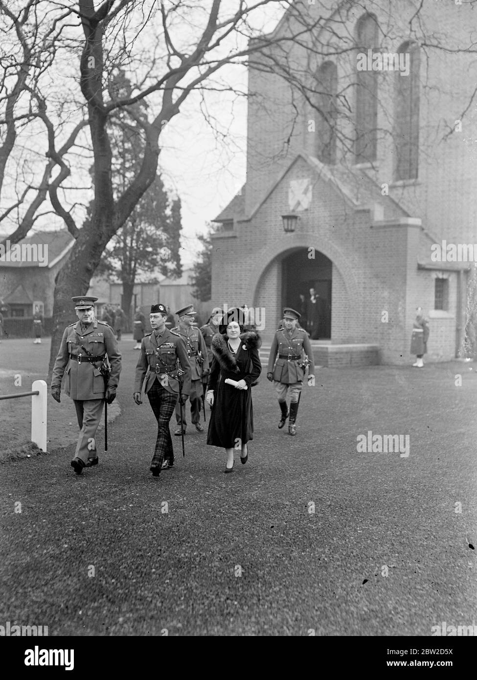The King George VI and Queen Elizabeth, who have just returned from Sandringham, attended the dedication of the new West Wing of the St Andrews Garrison Church of Scotland at Aldershot Camp, Hampshire, and afterwards inspected the Scots regiments. Photo shows: The King who is in uniform of one of the Scottish regiments, and the Queen leaving the church at Aldershot. 5 February 1939 Stock Photo