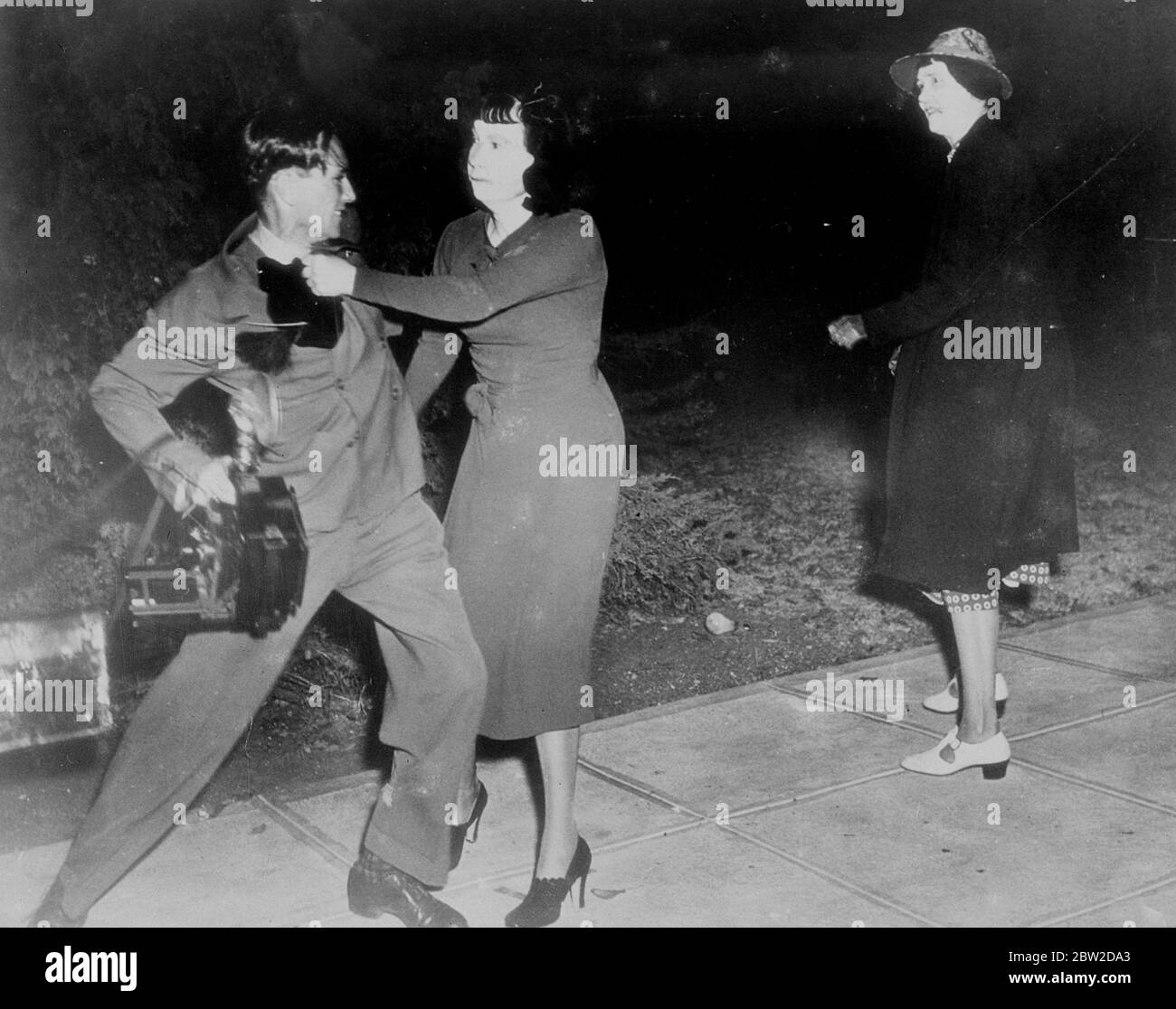 In a battle royale in front of the palatial home in Wiltshire Boulevard, Los Angeles, Mrs Anna Laura Barnett, white widow of Jackson Barnett, world's richest Indian [Native American] and her daughter routed the United States Marshall, who attempted to serve them an eviction order, and photographers. The women hurled numerous objects and the daughter came to grips with several other photographers. Mrs Barnett married the aged Creek Indian 13 years ago after oil was struck beneath his shack in Oklahoma. Later the courts ruled that marriage was invalid. Photo shows: Mrs Sturgis wrestles with Haro Stock Photo