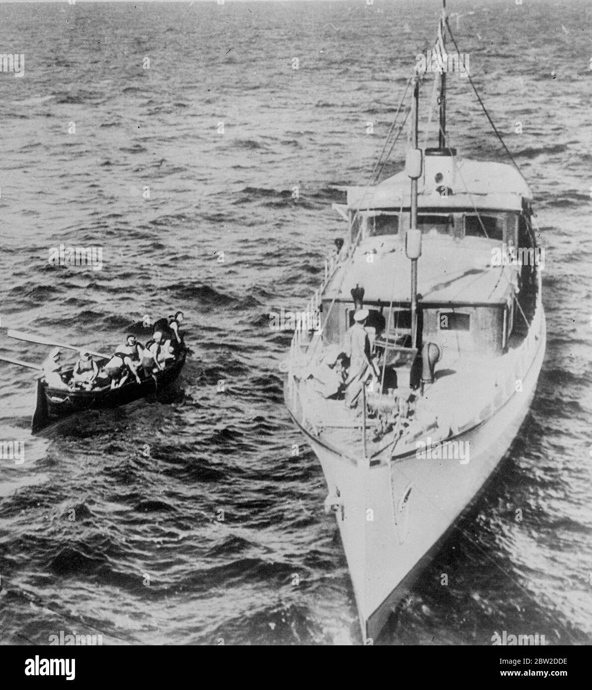 The sudden radio order which changed the course of the German freighter Schwaben led to the rescue of the disabled yacht Ling Dar, which was drifting in the Caribbean, far from usual shipping lanes. When the German ship found the yacht, the people aboard, including two women and a boy, was starving and had reached the last 2 gallons of fresh water. The freighter towed the yacht to Cartagena, Colombia, and resumed her voyage to Seattle. Photo shows: The rescue crew from the Schwaben pulling alongside the disabled yacht in the Caribbean Sea. 19 October 1938 Stock Photo