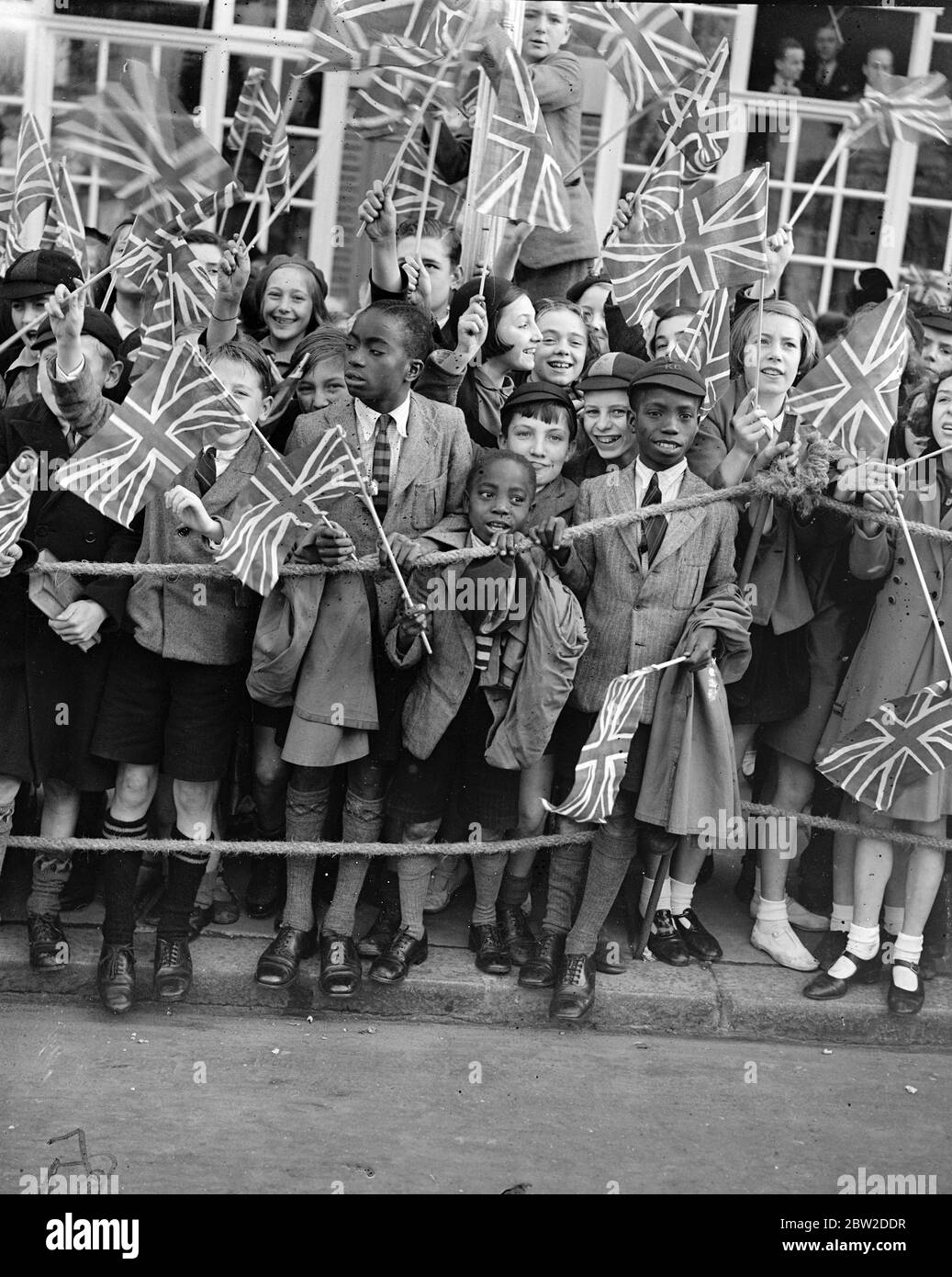1200 children, from more than 100 schools, were among the great crowds which cheered Queen Mary when she opened the new Â£90,000 extension to Lambeth Town Hall, Brixton. Photo shows: black children waving flags as Queen Mary arrived. 14 October 1938 Stock Photo