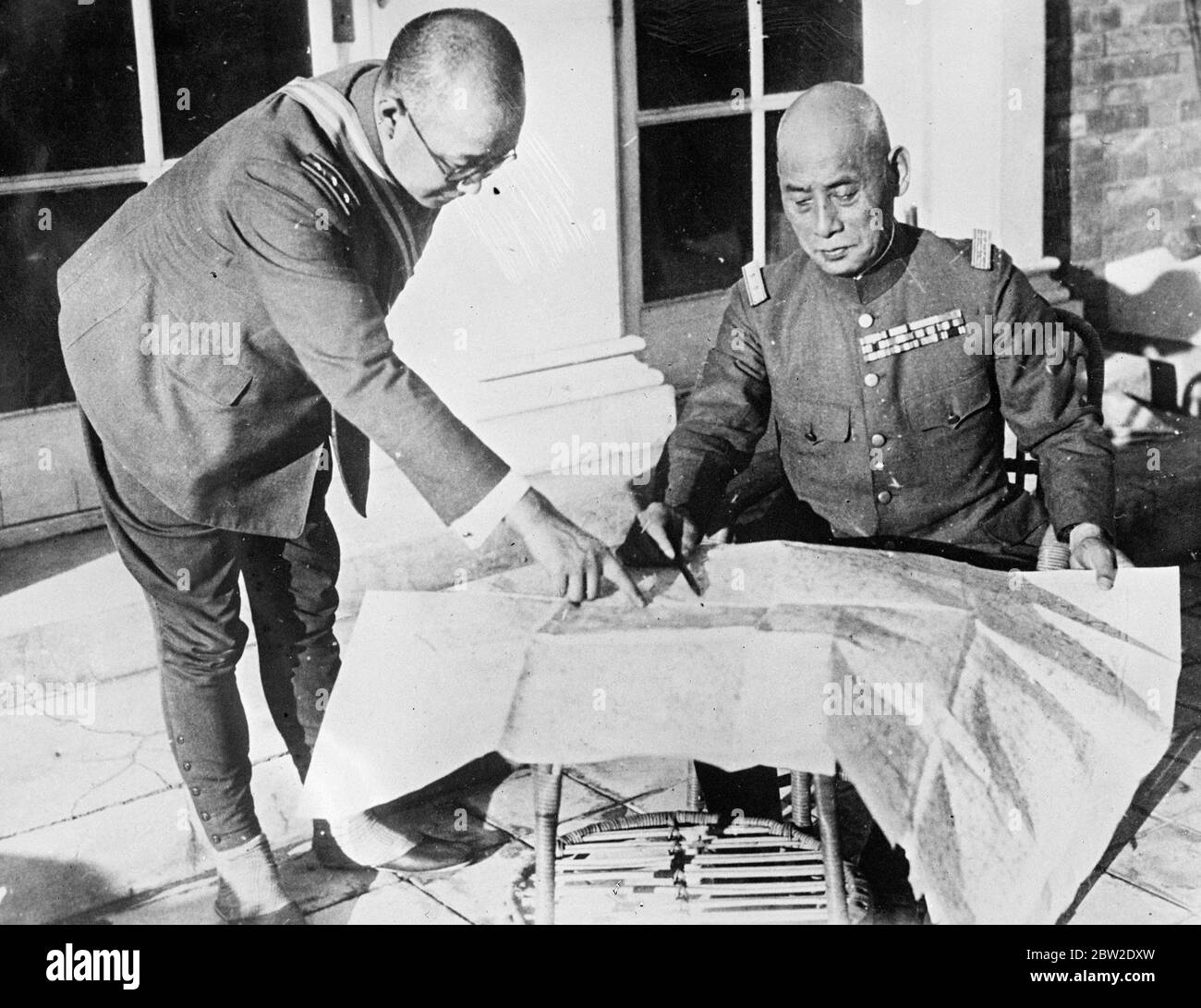 Lieutenant General Seiji Kazuki, commander in chief of Japan's north China garrison, consulting a map outside his headquarters, from where he is conducting operations against the Chinese. The fierce fighting which took place there between Chinese and Japanese troops. After Southern resistance by the Chinese took possession of the city when they carried out mopping up operations in the streets. Fighting is still going on in the south of the country. 23 August 1937 Stock Photo