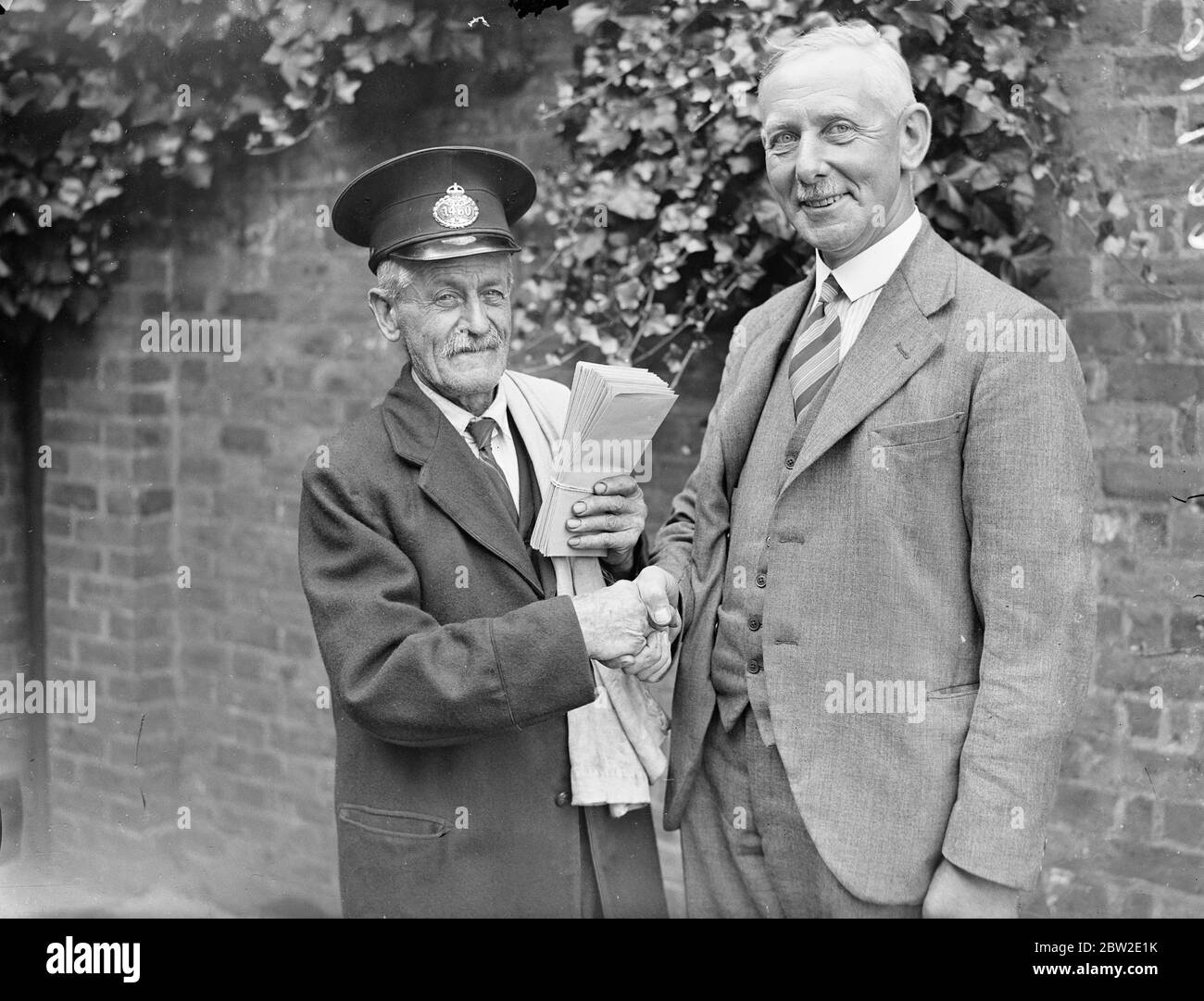 Mr John Brooks being congratulated by overseer EW Enmuns (right) he is reputed to be the oldest post man in London aged 72, of Southgate. He has now retired. 23 July 1937. Stock Photo