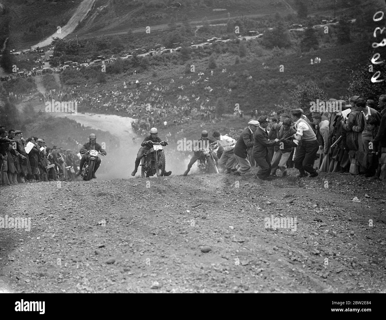 J Lilley of Sunbury club, being assisted by the crowd as other competitors, more fortunate, passed him on the steep hill at Bagshot. During wilde scramble of the Bayswater motorcycle club lived up to its name when several riders, in a flurry of dust, got out of control at a steep trial Hill and charged the crowd-fortunately without injury. 25 July 1937 Stock Photo