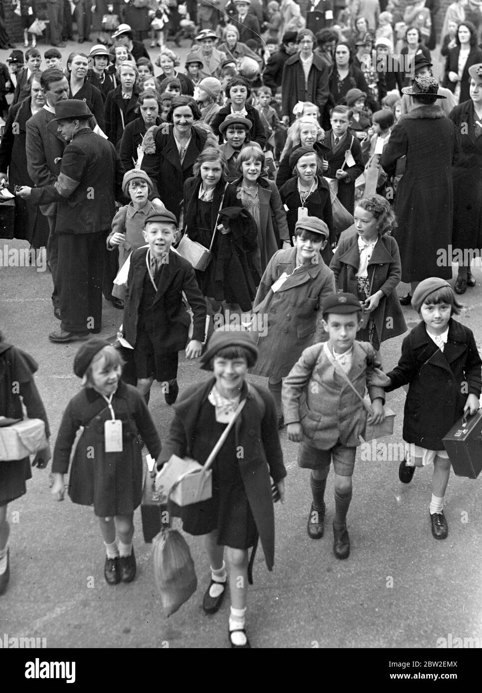 War Crisis, 1939. Air Raid precautions The Second World War began and evacuees like these in this picture, began to pour out of London for the safety of the countryside. Carrying gas-mask cases, with luggage labels identifying them fixed to their clothing - it was for some of them a Great Adventure for many of them had never left home, or even London before. Photo shows ; School children from Middlesex Street waiting for transport. 9 September 1939 Stock Photo