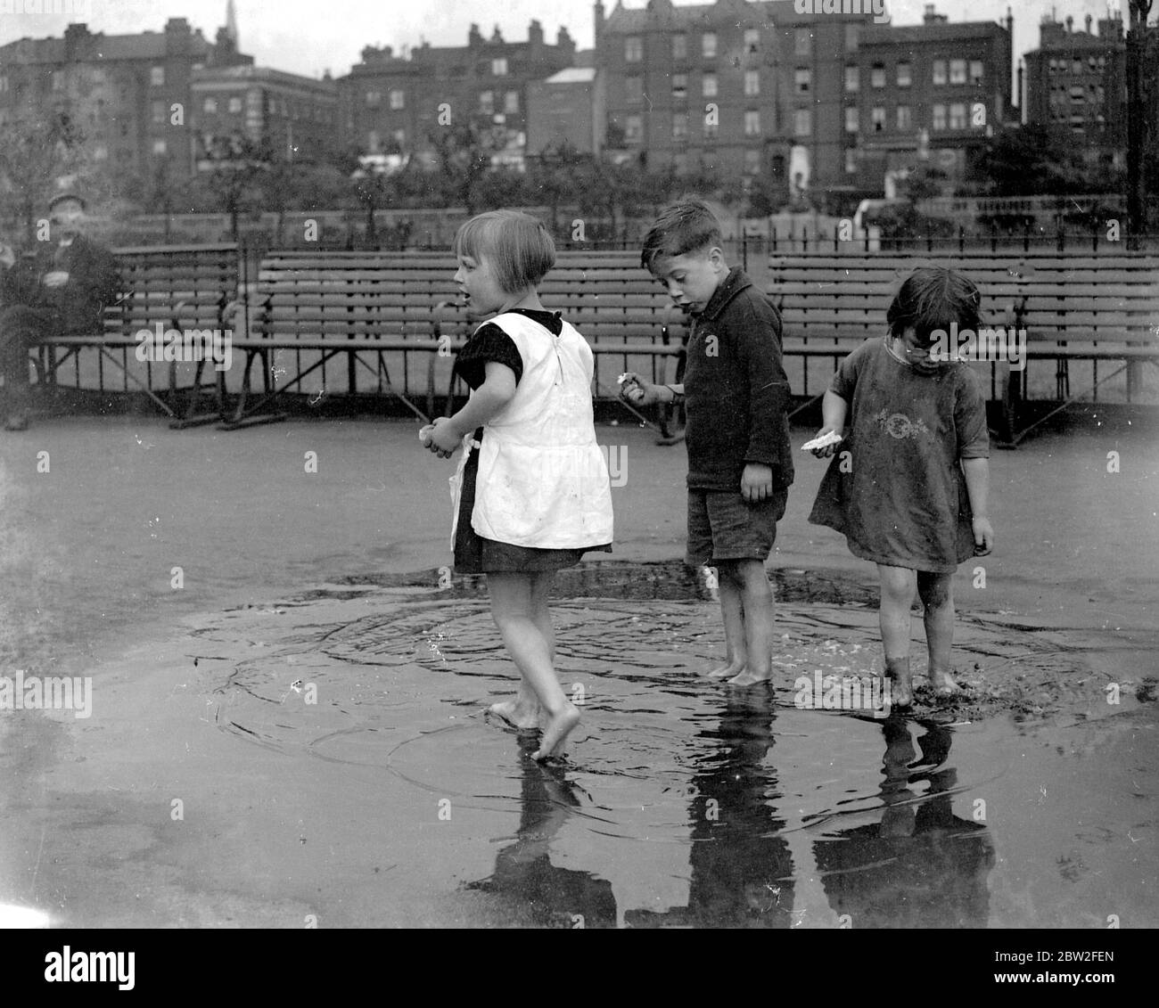 Small children paddling in a puddle in Wapping, London. 1933 Stock Photo
