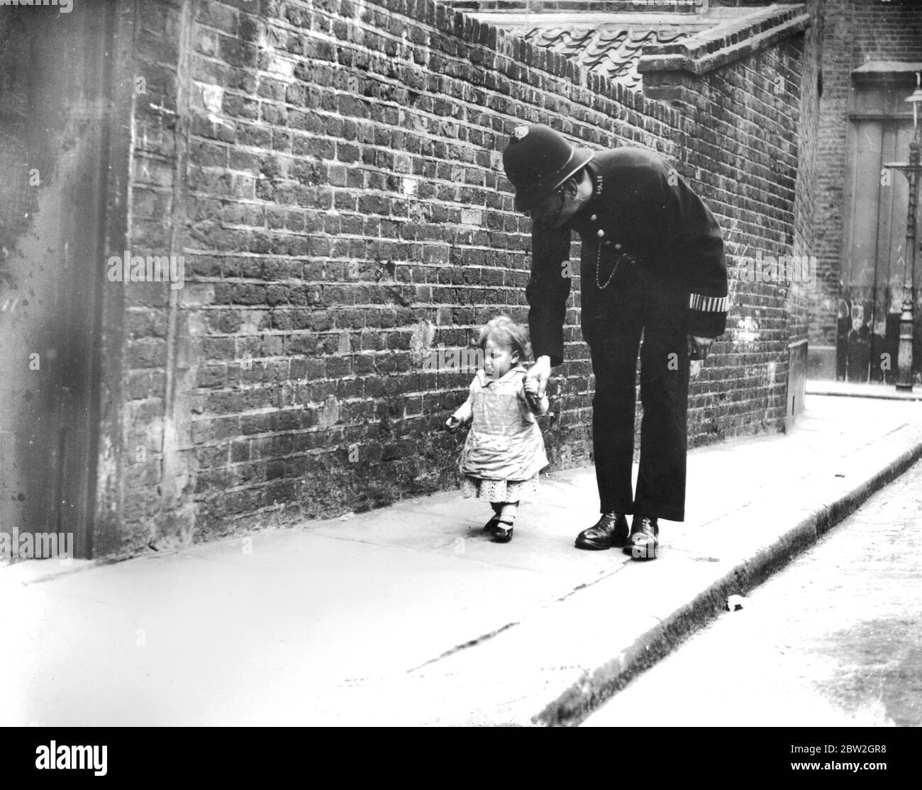 Children and toddlers played in the street, even a child of this age could be allowed to play outside wander off and come back with the care of the policeman on the beat. Stock Photo