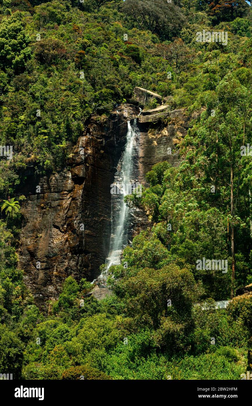 Waterfall with mountains and green trees around Stock Photo