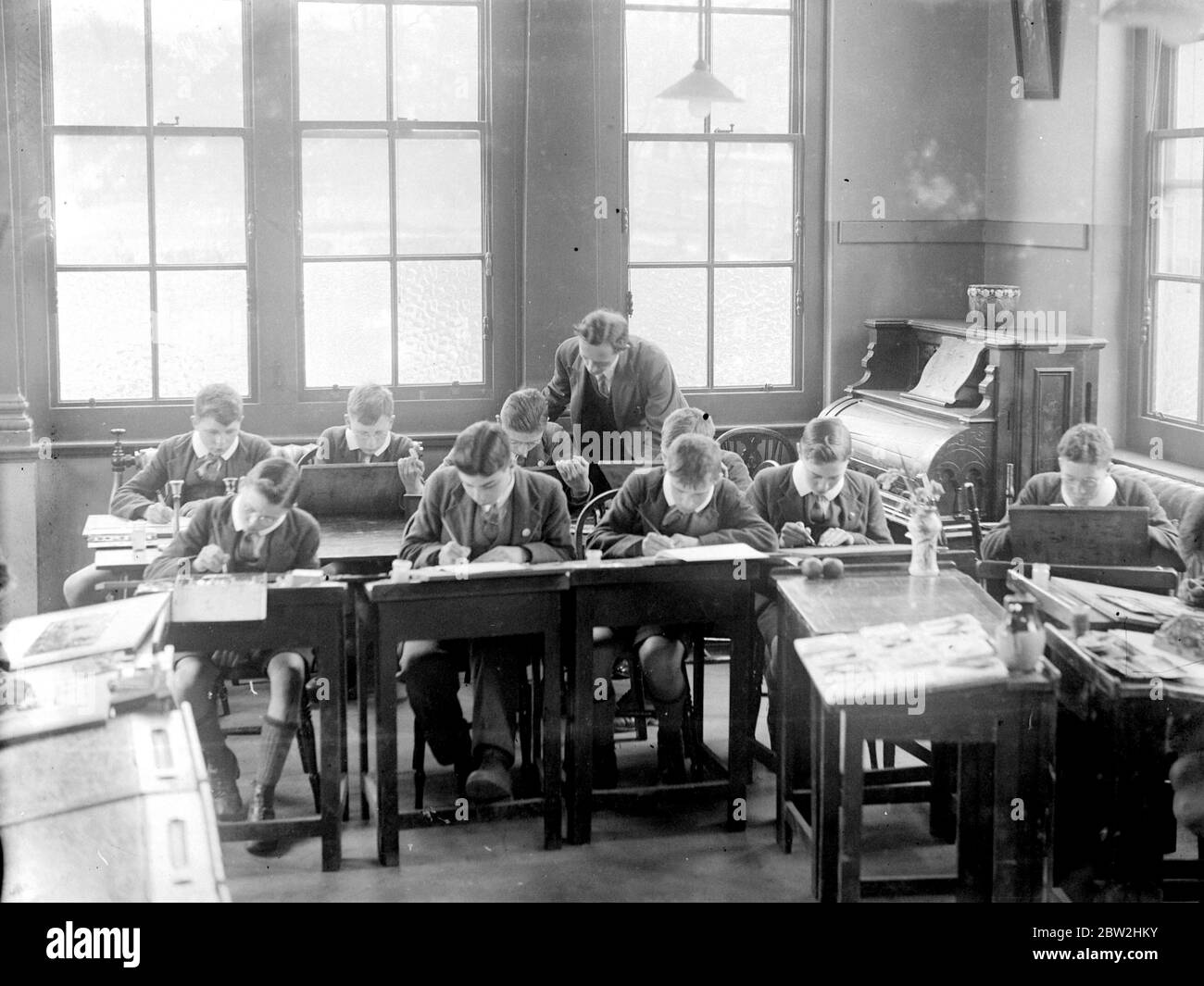 A teacher helps the boys with a lesson. 1933 Stock Photo