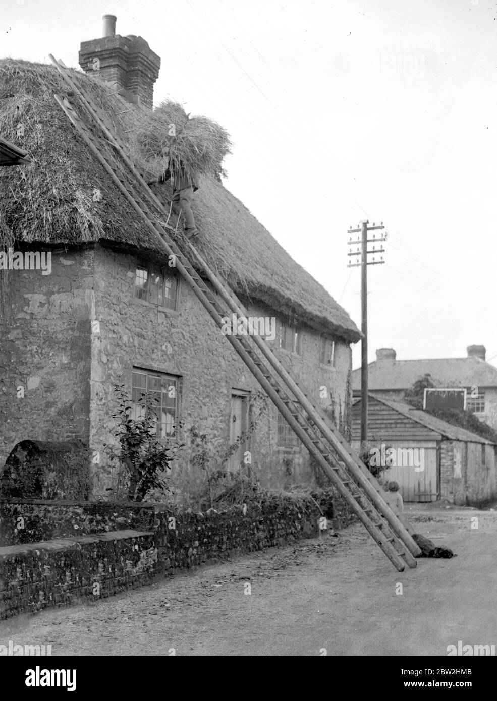 The craft of thatching - The thatcher at work on a picturesque Cottage at Amberley , Sussex . 20 November 1929 Stock Photo