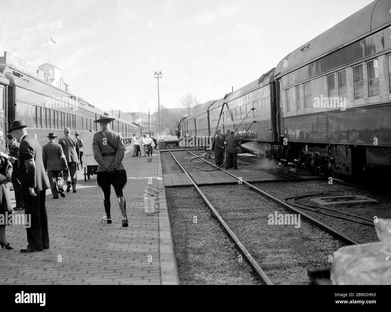 King George VI and Queen Elizabeth on their royal tour of Canada and the USA , 1939 . Railwaymen overhauling the Royal Train during a halt in Western Canada , the  Mountie  on duty and in the background men preparing to put ice aboard the train. Stock Photo
