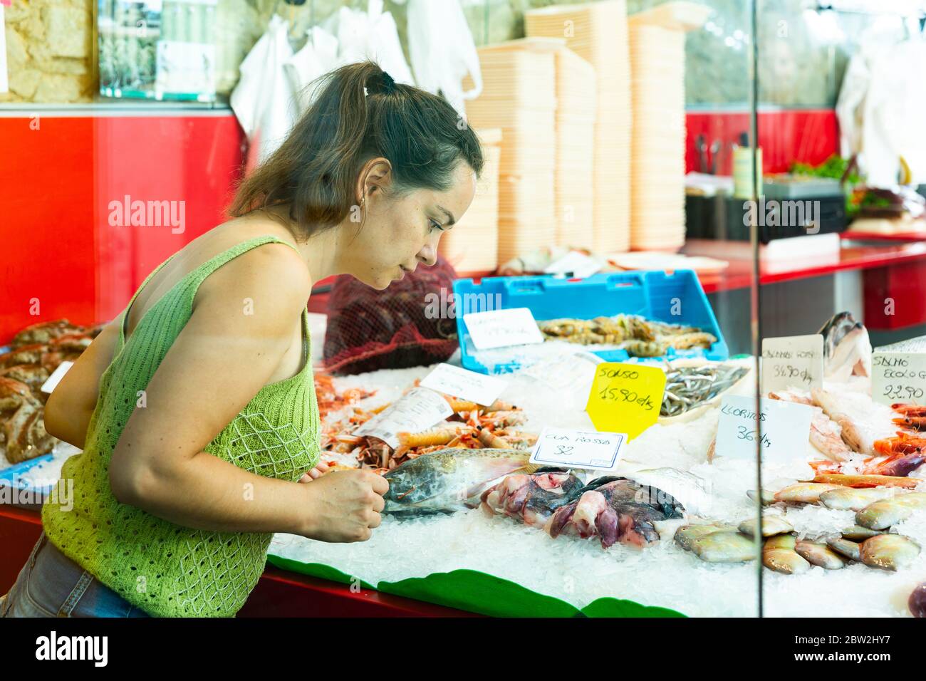 Portrait of female customer looking for fresh seafood in local fish ...