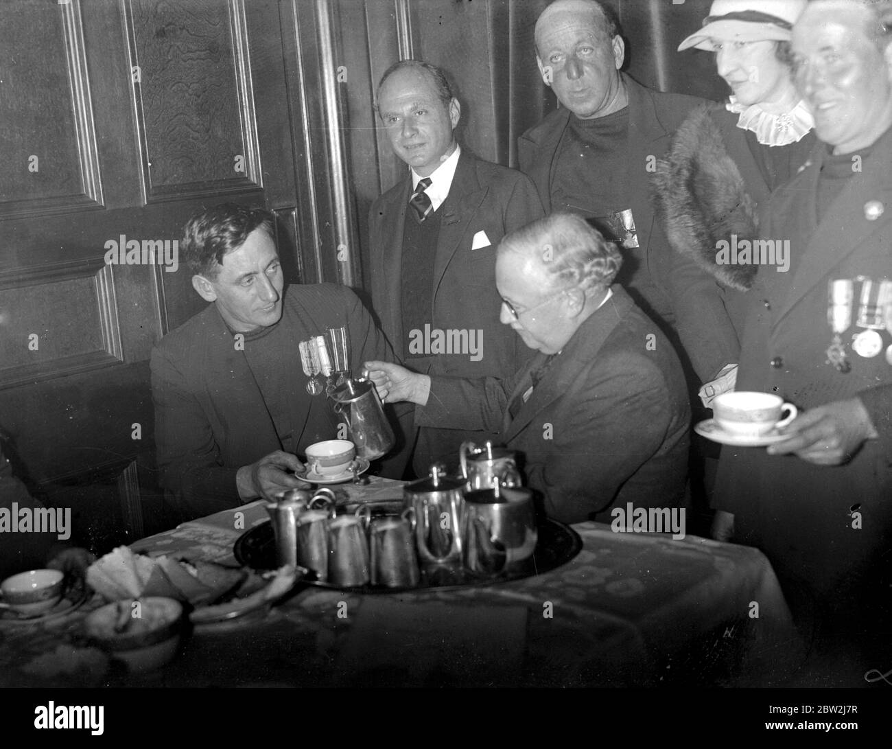 Skipper Cecil Richards of Hosebud and Sir Kingsley Wood (Minister of Health) take tea after presenting the petition brought by nine newlyn fishermen protesting against the demolition of their cottage homes, condemed under a slum clearance scheme. 22 October 1937 Stock Photo