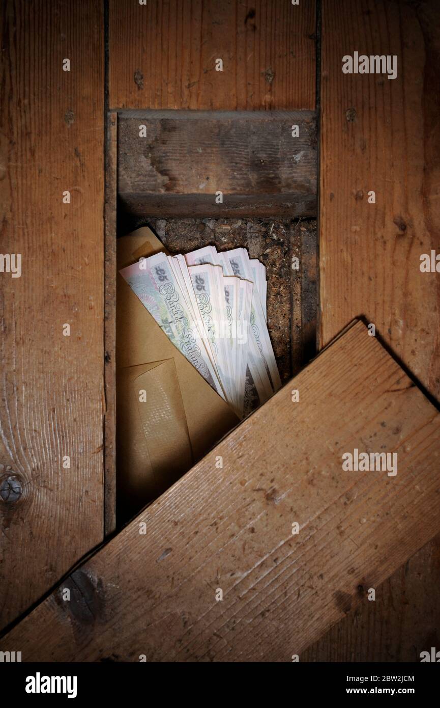 An envelope of money under some wooden floorboards Stock Photo