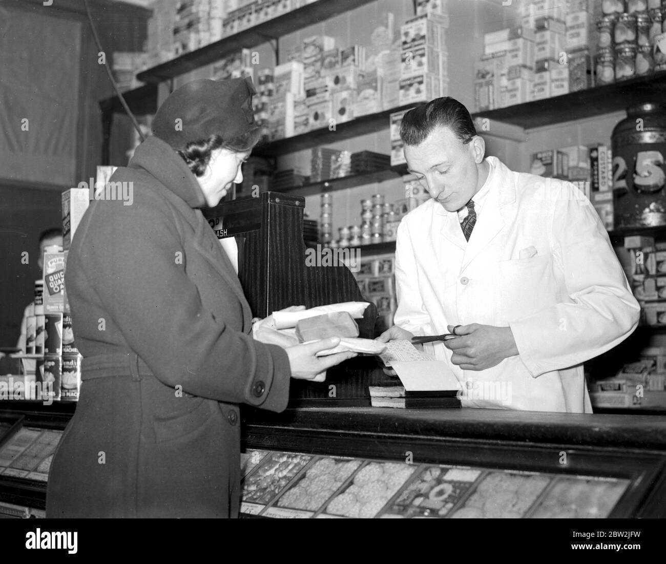 War 1939-1940. Rationing - cutting out the coupons for sugar at the grocer's. 8 January 1940 Stock Photo