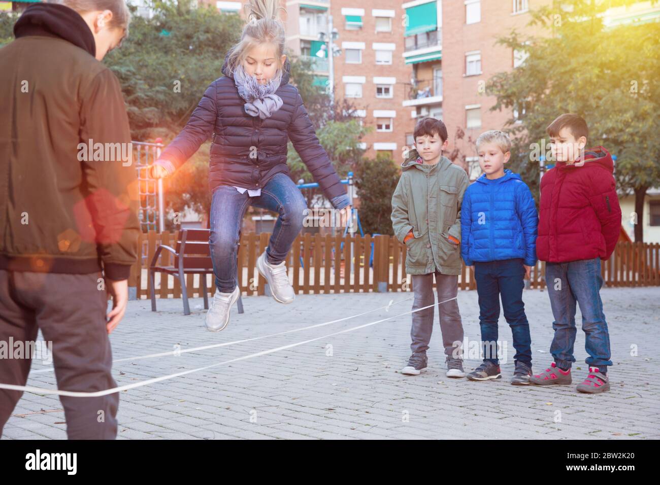 Children jump through an elastic rope in a children playground Stock ...