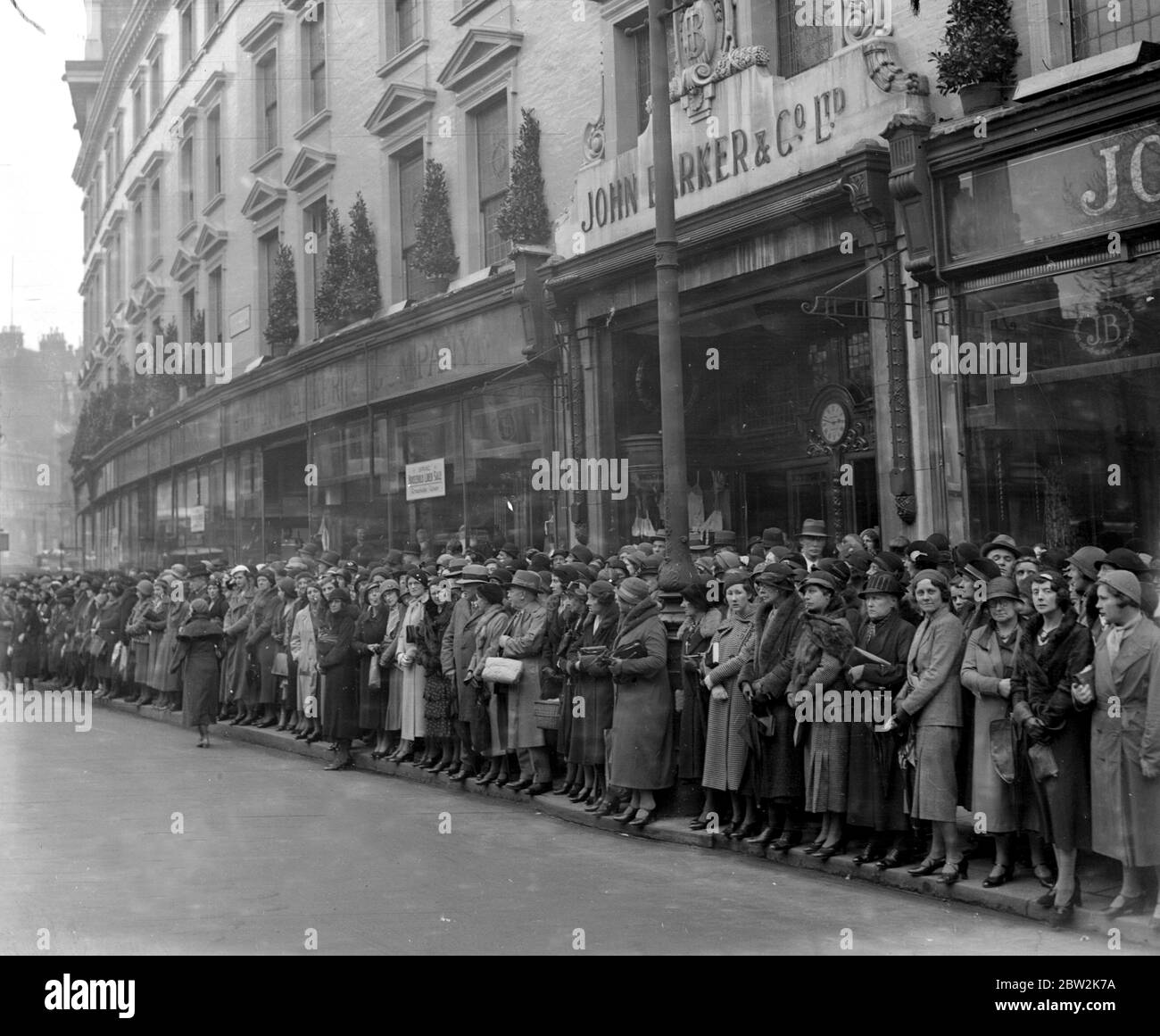 A shopping crowd in Kensington turns its back on the window display to watch the wedding of Hon James Lindsay and Hon Bronwen Scott-Ellis at St Mary Abbotts. 26 April 1933 Stock Photo