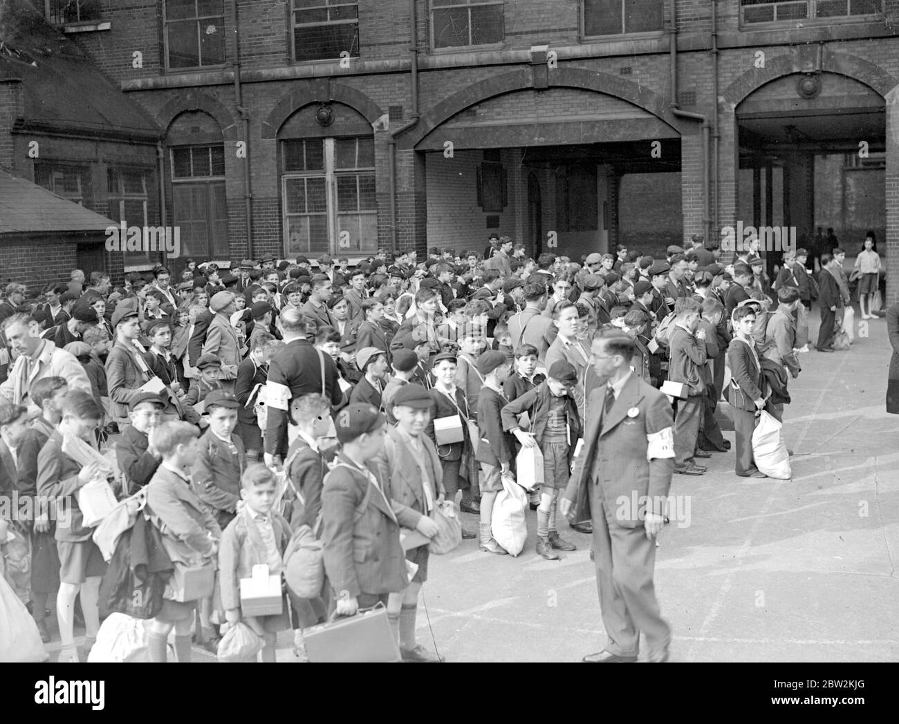 War Crisis, 1939. Air Raid precautions Second World War began, and evacuees, like these in this picture, began to pour out of London for safety of the countryside. Carrying gas-mask cases, luggage labels identifying them, fixed to their clothing, it was for some of them a Great Adventure, for many of them had never left home, or even London before. Schoolchildren from Middlesex Street waiting for transport. 9 September 1939 Stock Photo