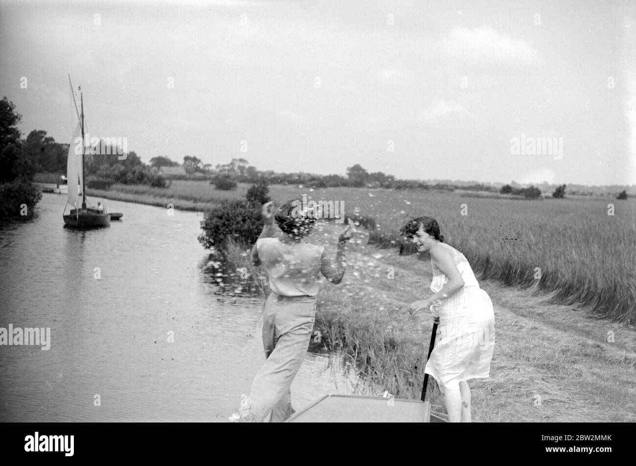 The Broads, Norfolk. Women splashing water on a barge on a canal. 1934 Stock Photo