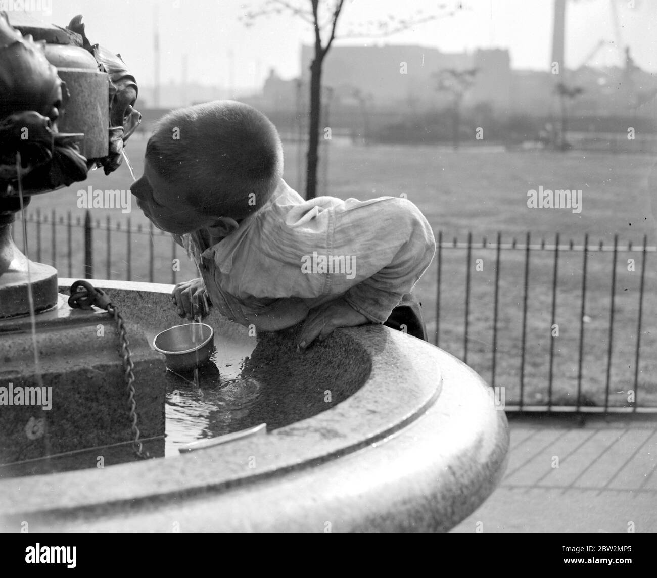 London summer. A little boy drinks water from a fountain. 1933 Stock Photo