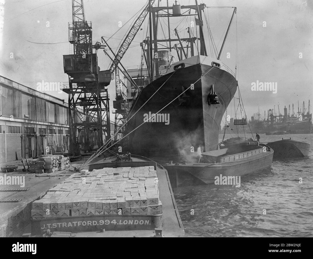 Sunday unloading to escape Tariffs . All day Sunday the Thames docks presented a scene of unprecedented activity as ships were unloaded and goods transferred to barges and hurried ashore to escape the new tariffs . Unloading the President Harding the American liner which docked for the first time at the King George Vdocks . 28 February 1932 30s, 30's, 1930s, 1930's, thirties, nineteen thirties Stock Photo