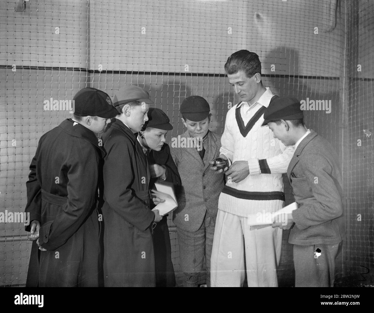 Harold Larwood a professional cricketer for Nottinghamshire shows children how to hold the ball . 9 April 1934 Stock Photo