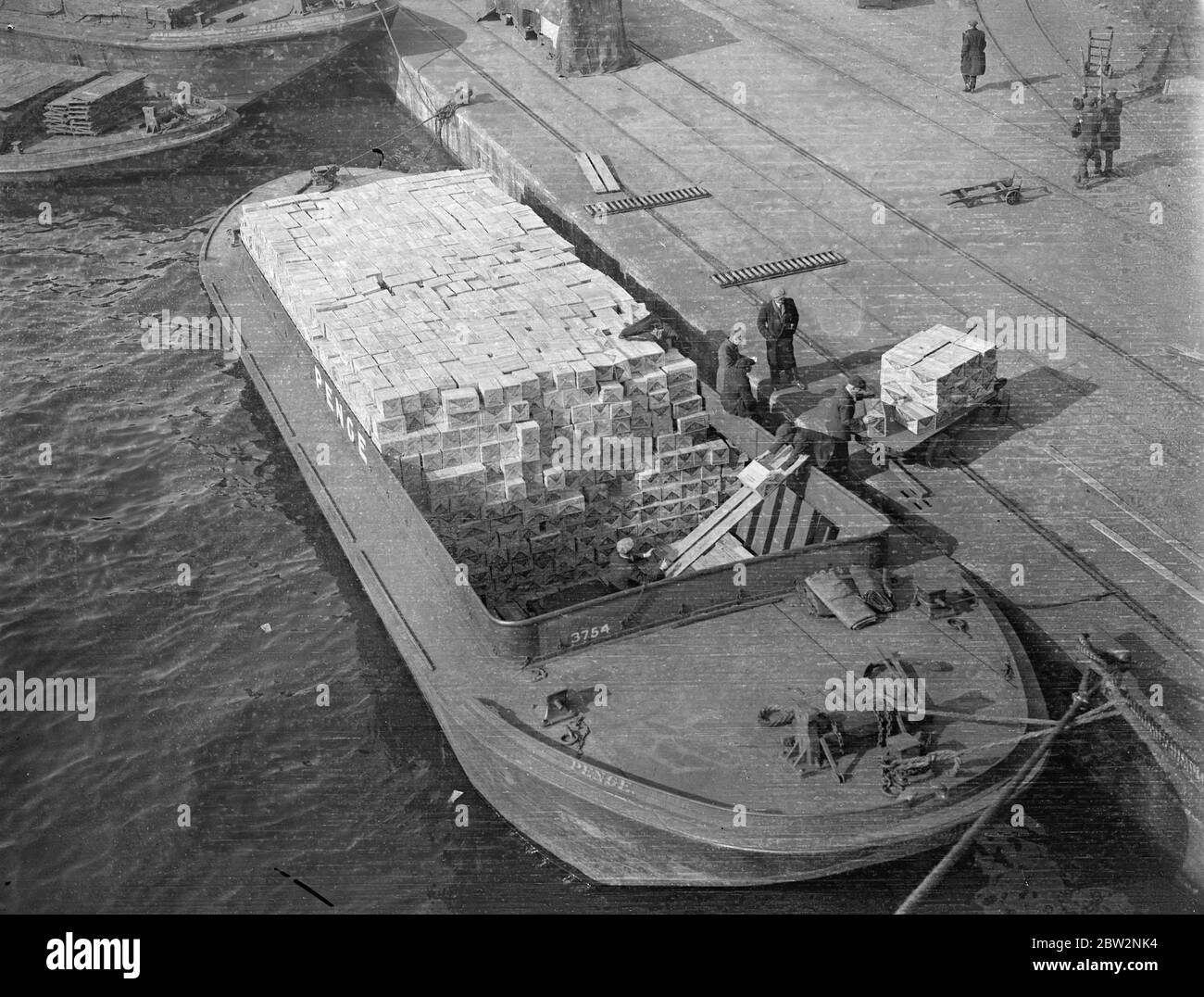 Sunday unloading to escape Tariffs . All day Sunday the Thames docks presented a scene of unprecedented activity as ships were unloaded and goods transferred to barges and hurried ashore to escape the new tariffs . Unloading milk from the President Harding the American liner which docked for the first time at the King George Vdocks . 28 February 1932 30s, 30's, 1930s, 1930's, thirties, nineteen thirties Stock Photo