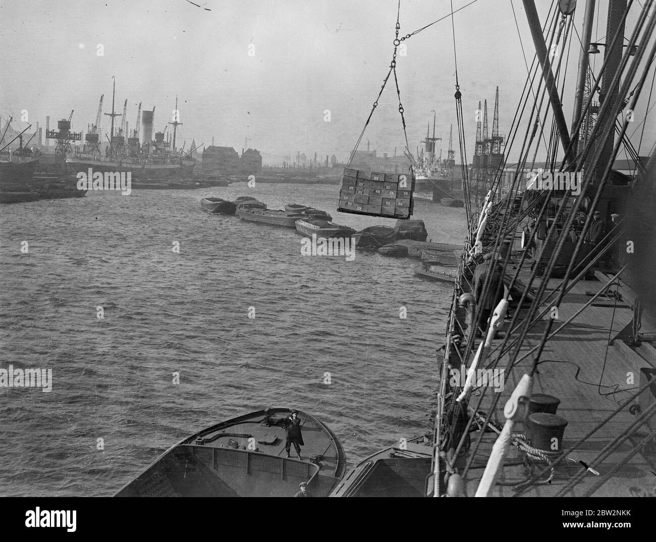 Sunday unloading to escape Tariffs . All day Sunday the Thames docks presented a scene of unprecedented activity as ships were unloaded and goods transferred to barges and hurried ashore to escape the new tariffs . Unloading milk from the President Harding the American liner which docked for the first time at the King George Vdocks . 28 February 1932 30s, 30's, 1930s, 1930's, thirties, nineteen thirties Stock Photo