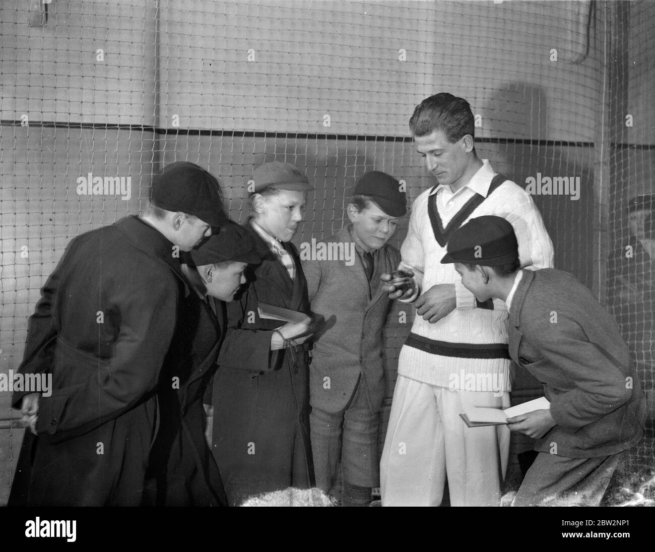 Harold Larwood a professional cricketer for Nottinghamshire shows children how to hold the ball . 9 April 1934 Stock Photo