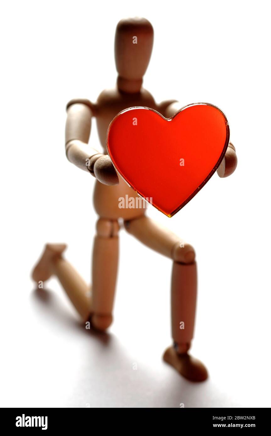 A wooden mannequin proposing with a red heart shape Stock Photo