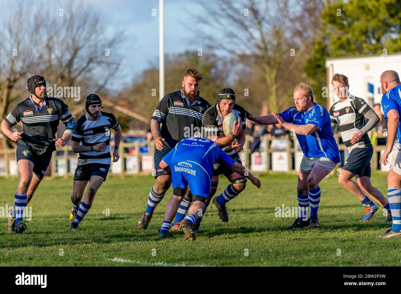 Rugby players carrying the ball crouches to push off a tackling player crouching. Eastern Counties rugby union match at Lowestoft Stock Photo
