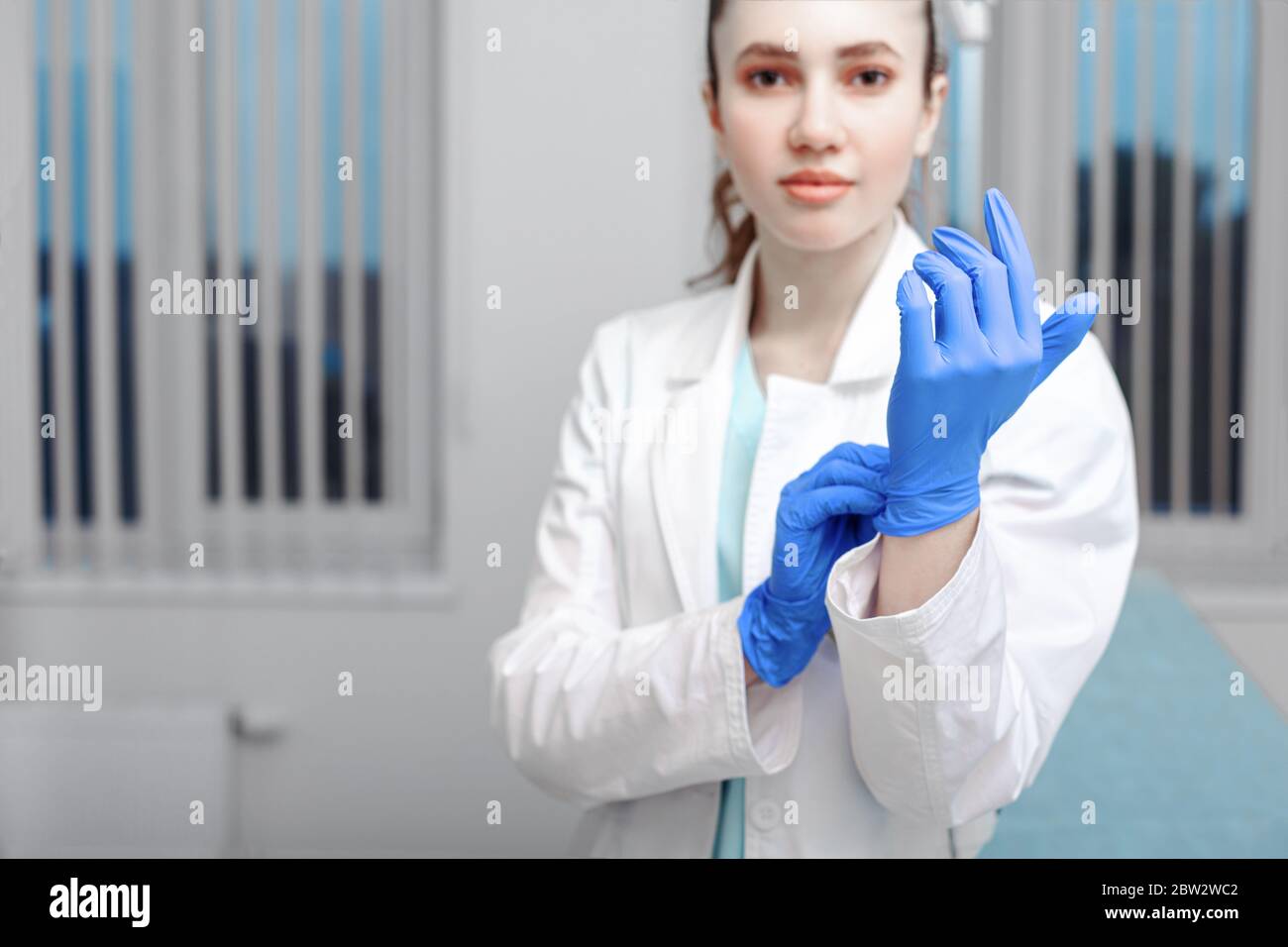 Doctor's hands putting on latex gloves in a hospital. Woman in a doctor
